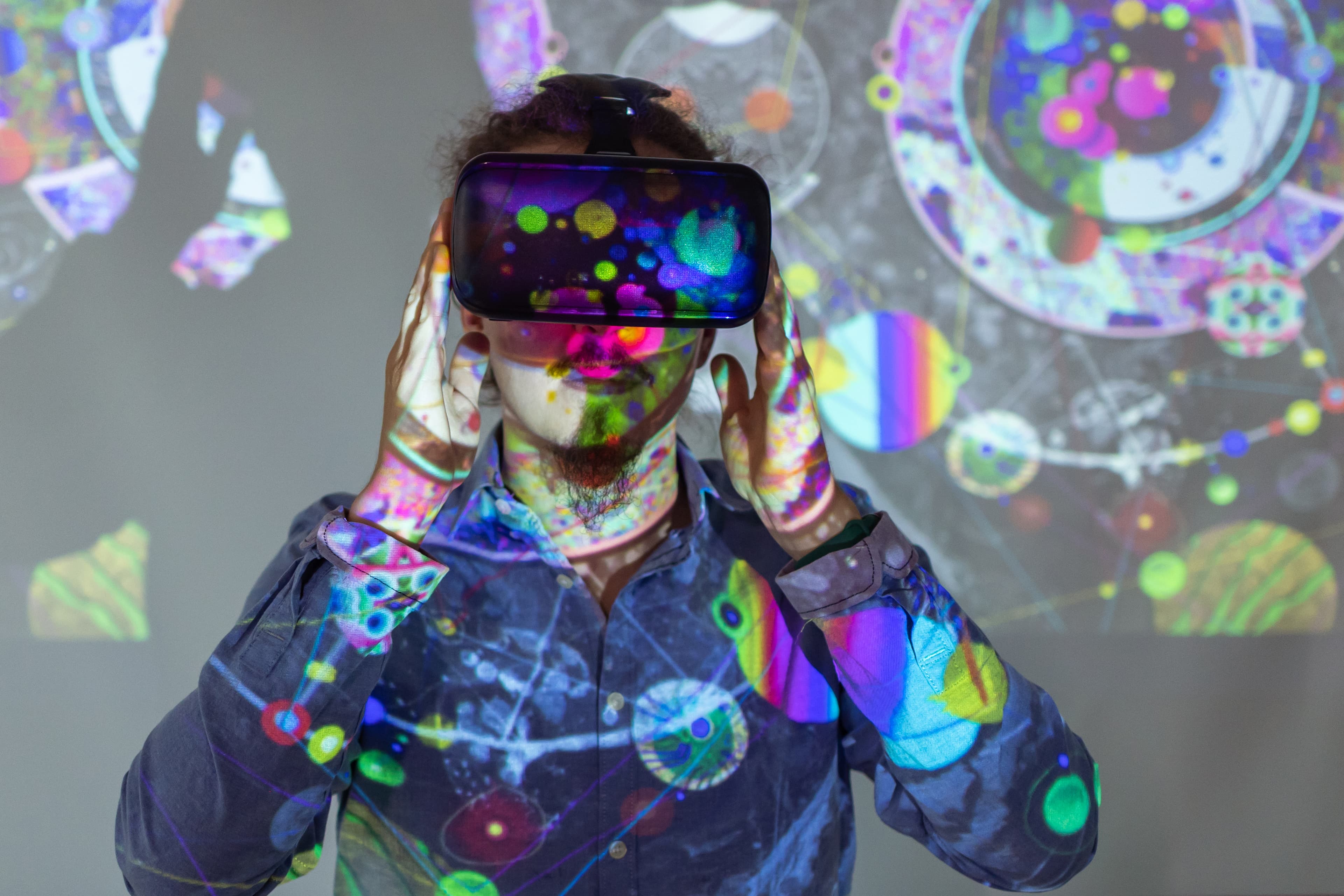 Person wearing VR headset with colorful abstract projections on them and the background.